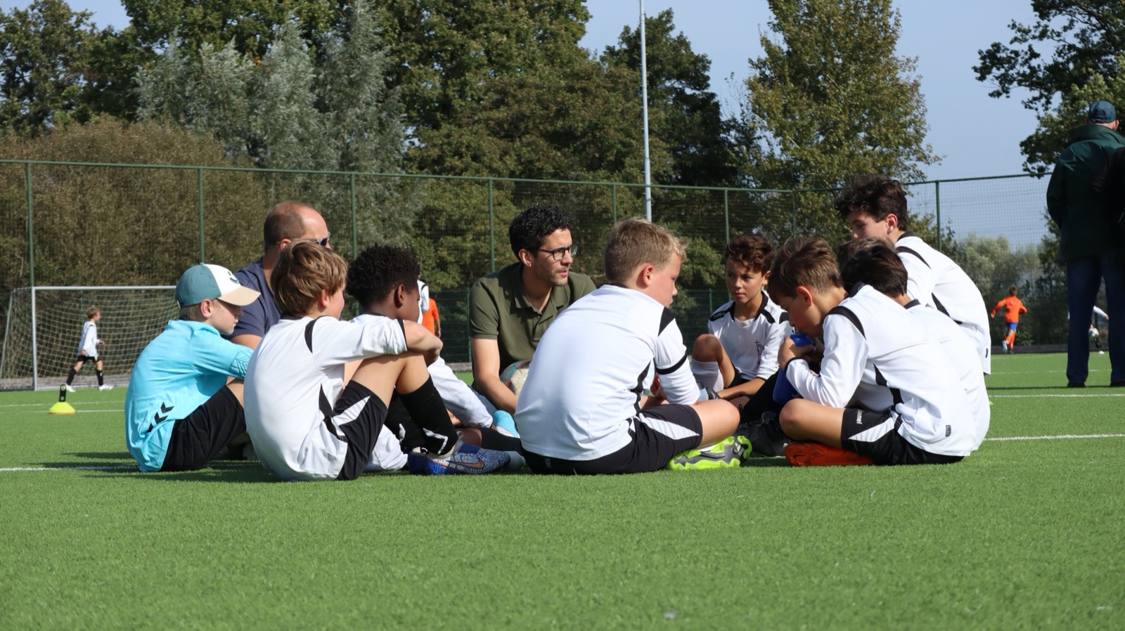 Gido in gesprek met zijn jeugdteam op het veld